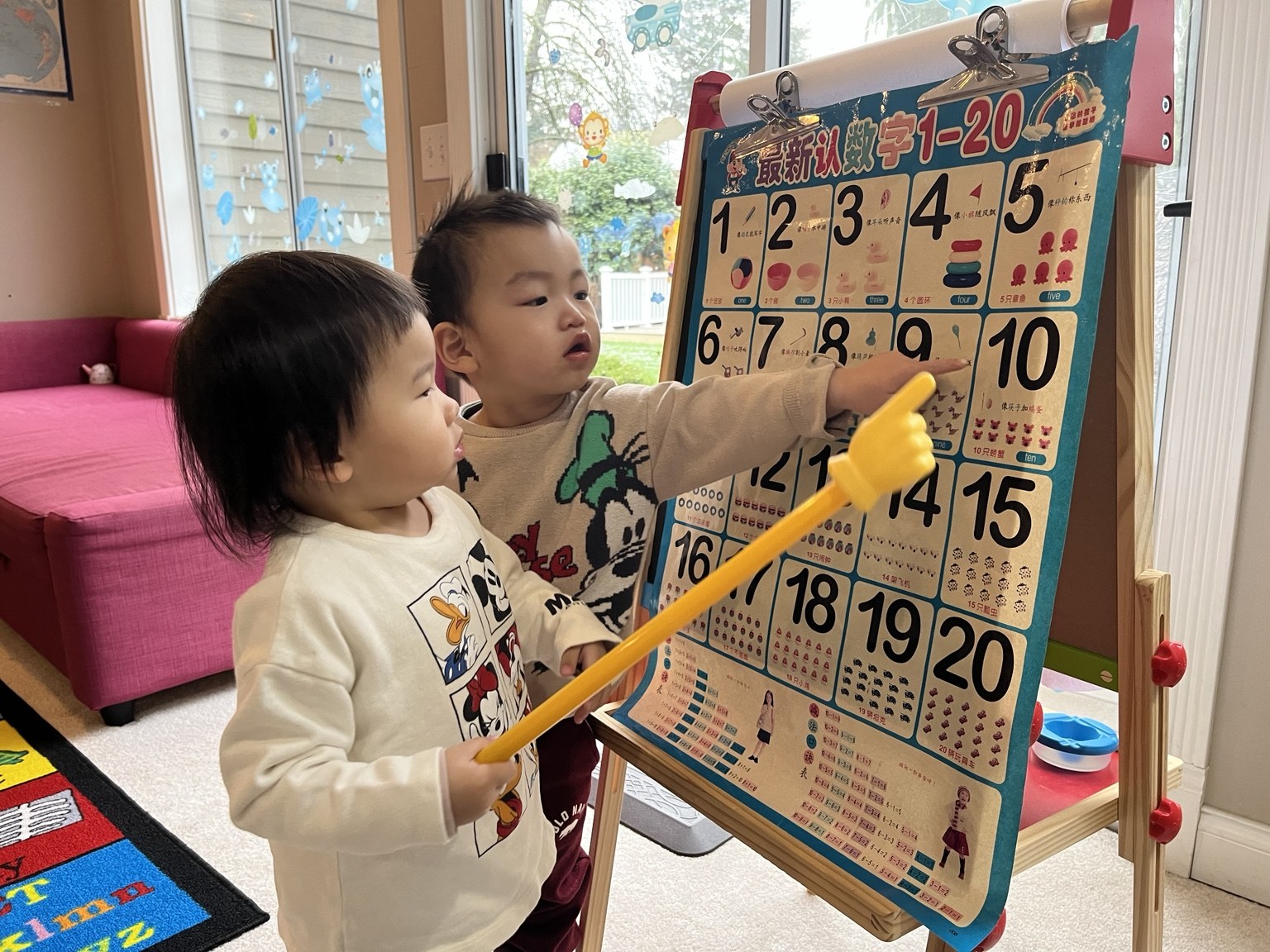 Two children practicing numbers together at a classroom learning board